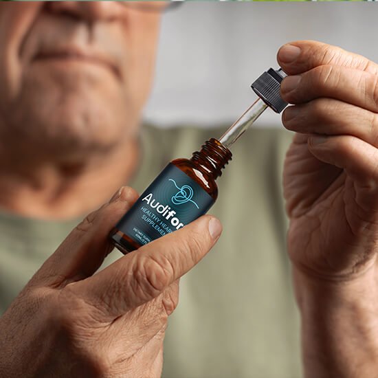 Close-up of an older man holding a amber glass bottle of Audifort healthy hearing liquid supplement and extracting a liquid dose with a dropper.